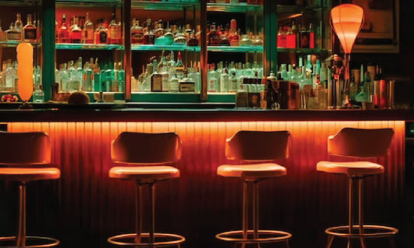 Empty bar with orange lighting and bar stools in the foreground